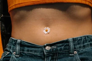 photo - a woman with a flower in her navel wondering about belly button piercing healing timeline