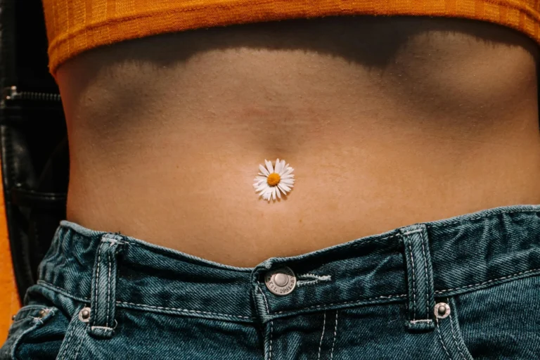 photo - a woman with a flower in her navel wondering about belly button piercing healing timeline